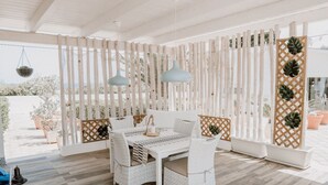 Una stanza luminosa e spaziosa con un divano bianco e un tavolo, con uno sfondo a pannelli in legno traforato.