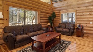 A log cabin interior with two leather sofas, a wooden coffee table, and a chandelier. - Rocky Mountain cabin w/ fireplace & deck (Grand Lake)