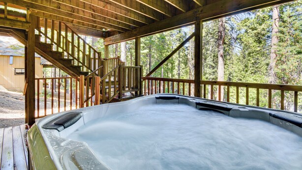 Una vasca idromassaggio in una cabina di legno con una scala che conduce a un patio.