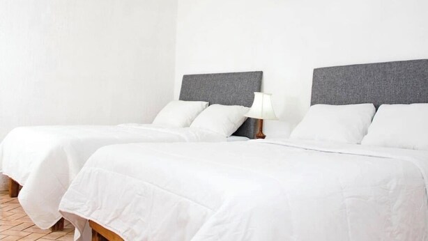 Een hotelkamer met twee bedden, een plafondventilator en een nachtkastje met een lamp.