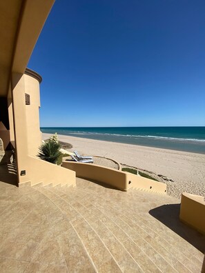 A beach view from a building with a staircase leading to a terrace with lounge chairs. - UPSCALE Beachfront Amazing 5 bedrooms. Pet Friendly! (Puerto Peñasco)