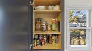 A kitchen pantry with shelves stocked with jars, spices, and kitchenware. - Modern 4 Bedroom Beach House: Ideal for Families & Long Stays (West Haven)