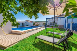 A swimming pool, a covered seating area, and a grassy lawn.