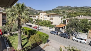 Zona residencial con edificios de varios pisos, una calle con automóviles estacionados y una palmera.