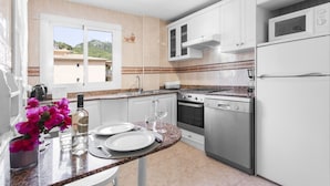 Cocina con alacenas blancas, encimera de granito, horno de acero inoxidable y lavavajillas.