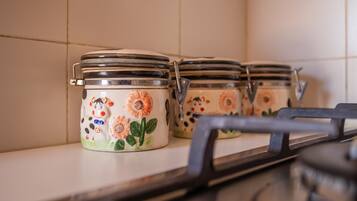 Potes de cerâmica com motivos florais numa prateleira de cozinha.