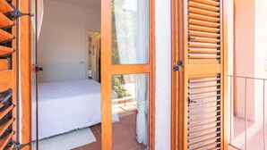 Une chambre à coucher avec un lit, une fenêtre et une porte avec des volets.
