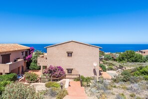 A building with a flat roof, a satellite dish, and a view of the sea.
