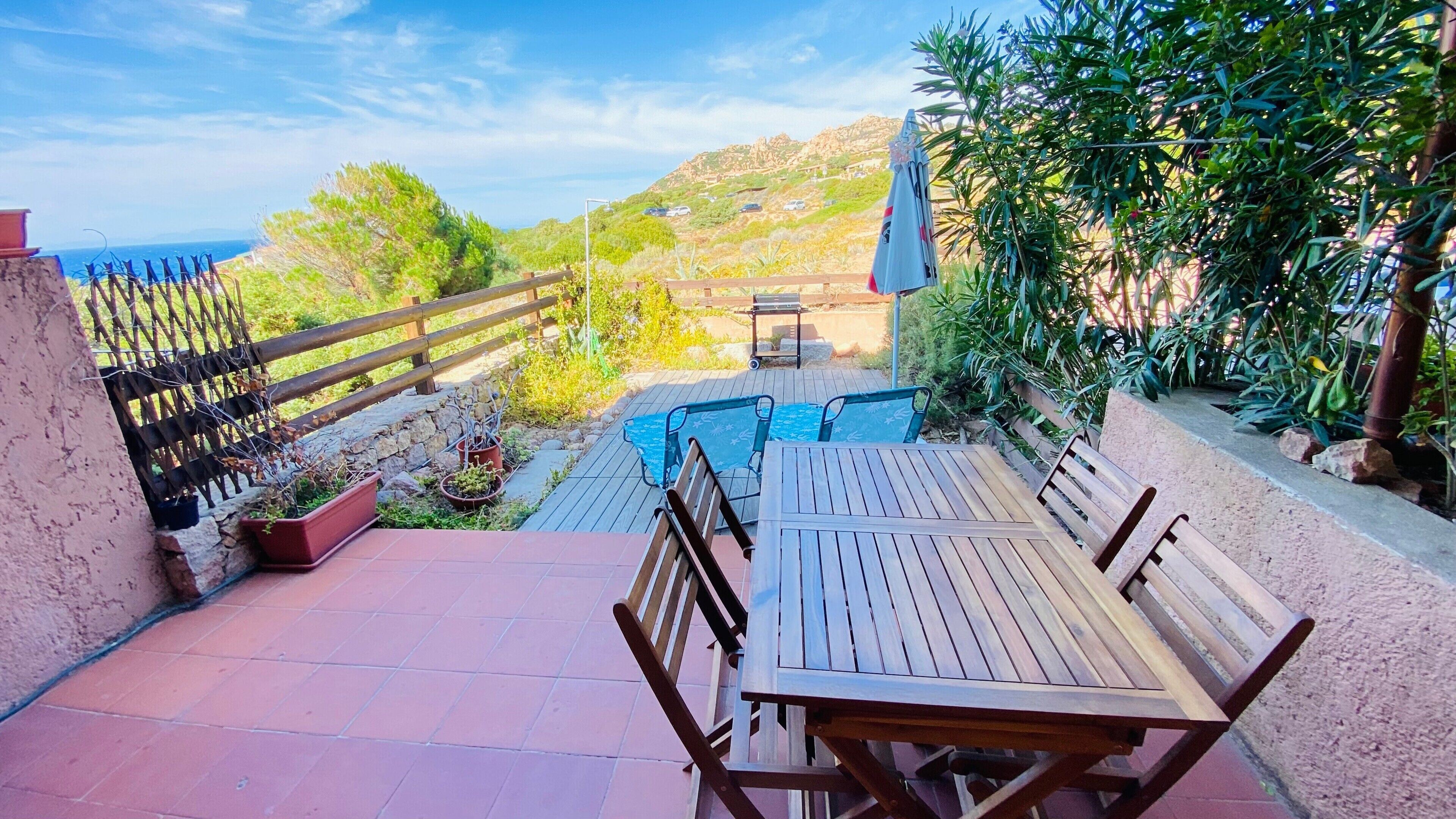 Eine Terrasse mit Holztisch und -stühlen, einem kleinen Pool und Meerblick.