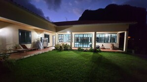 Une maison moderne dotée d’une pelouse bien entretenue, de grandes fenêtres et d’une piscine.