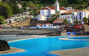 Un resort costero con una gran piscina, villas frente a la playa y una iglesia.