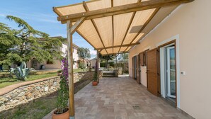 A covered patio area with stone flooring, potted plants, and a wooden pergola structure. - Farmhouse 'Al Posto Giusto - Gioia' with Shared Garden, Wi-Fi and Air Conditioning (Riotorto)