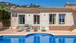Un espace aménagé au bord de la piscine, offrant une vue dégagée sur celle-ci, avec deux chaises longues et un panier de basketball.