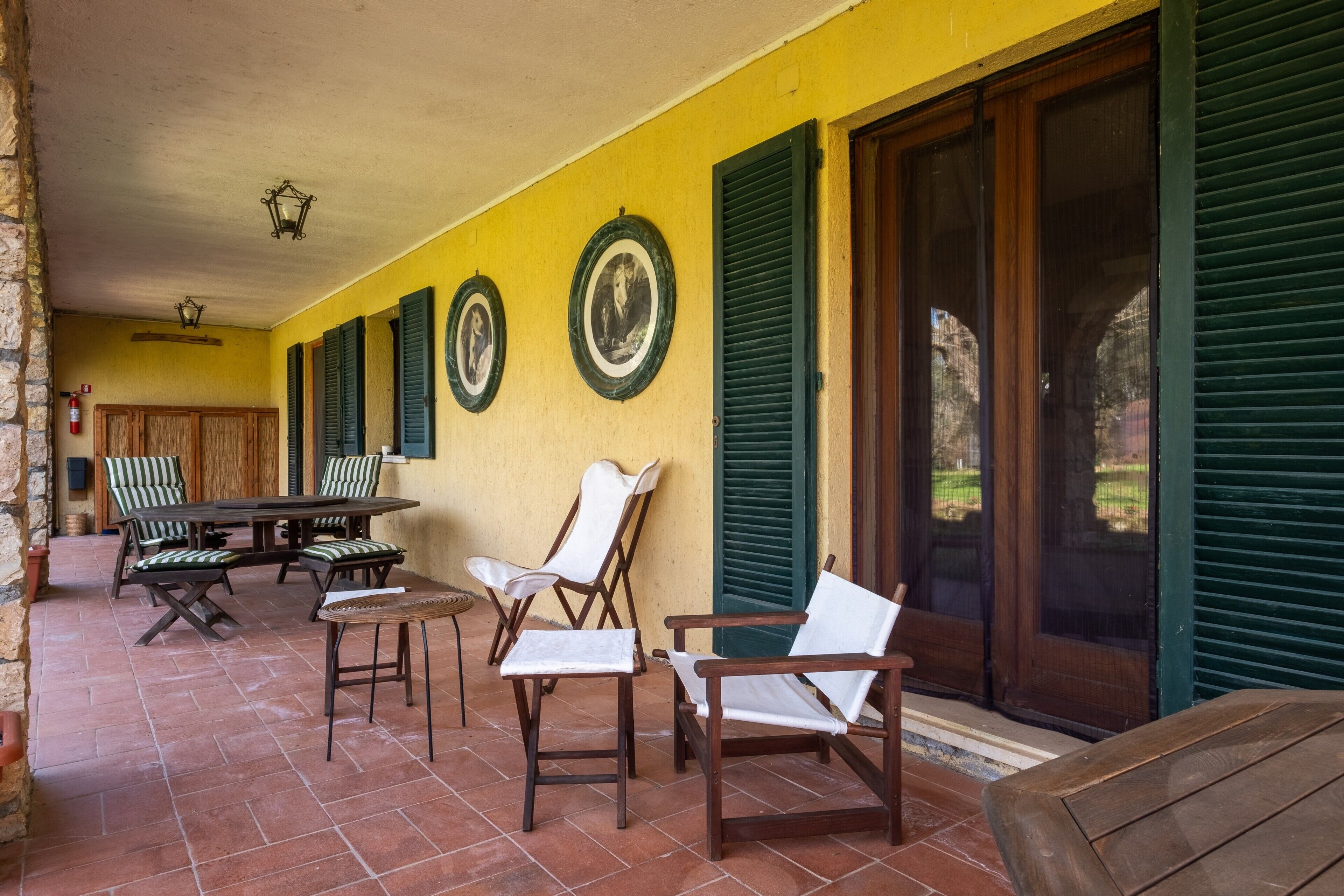 A covered patio with outdoor furniture, a wooden table, and chairs.