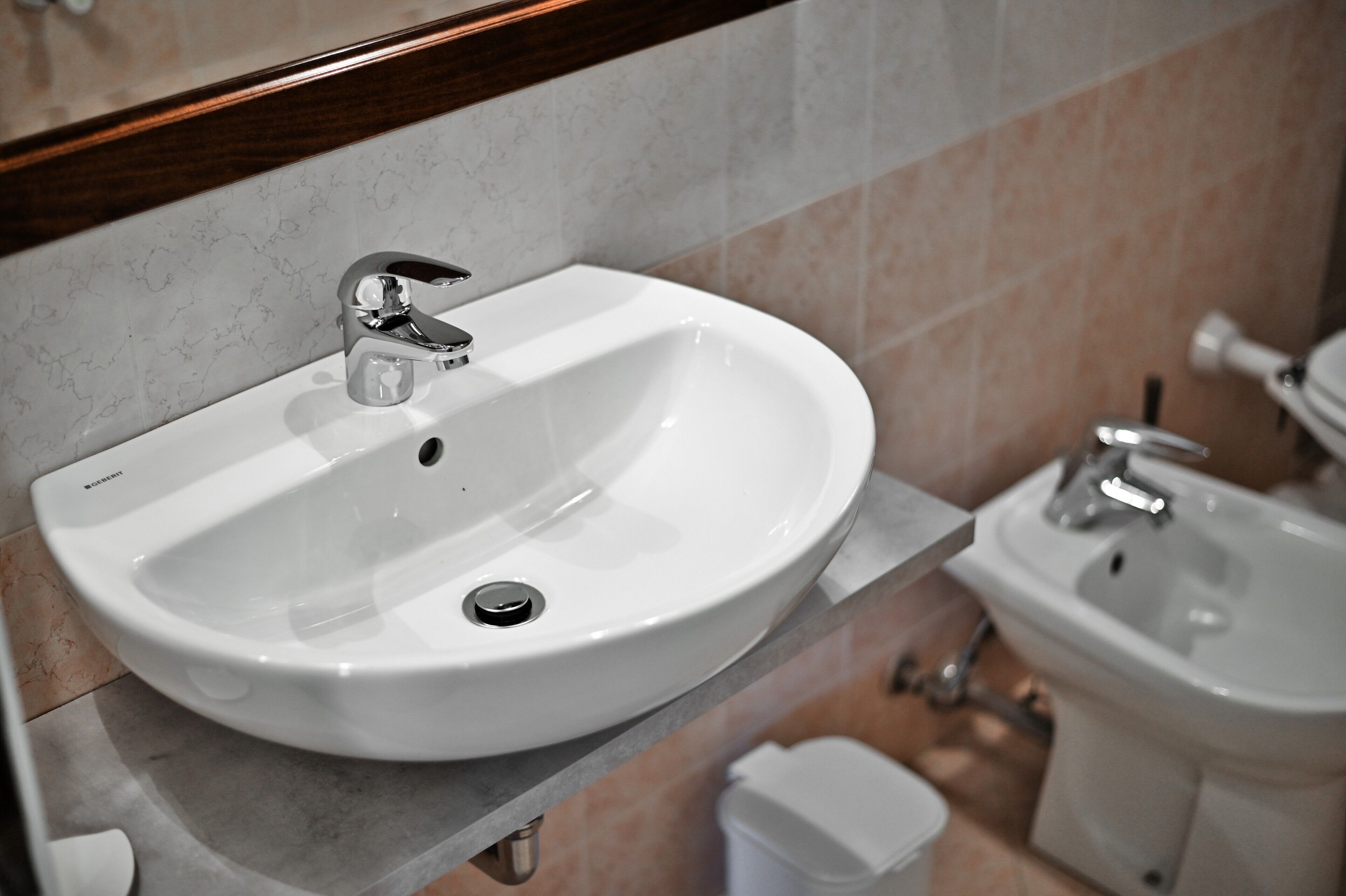 A bathroom with a white sink, a bidet, and a toilet.