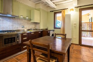 Une cuisine avec une table et des chaises en bois, un four encastré et un lave-linge.