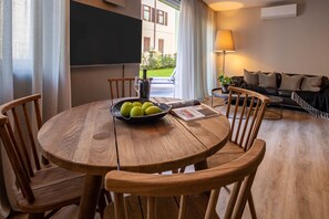 A wooden dining table with chairs, a bowl of fruit, and a bottle of water.