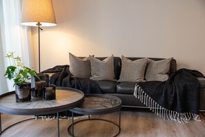 A modern living room with a sofa, two round coffee tables, a floor lamp, and a potted plant.