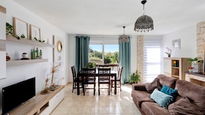 A living room with a TV, dining table, chairs, a brown sofa, and a chandelier. - Holiday Home "Duplex India" with Wi-Fi (Tacoronte)