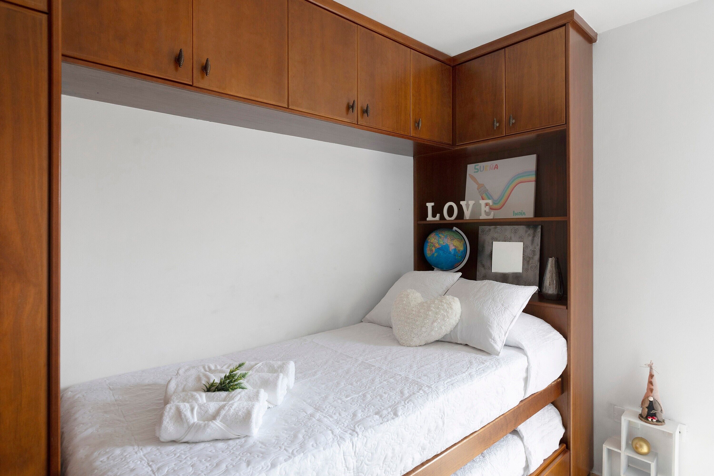 Un dormitorio con cama, armario de madera y un globo en la pared.