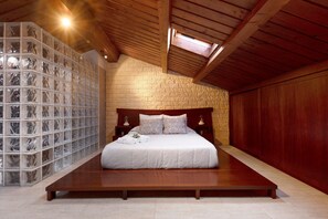 A bedroom with a wooden bed, a stone wall, and a skylight. - Holiday Home "Duplex India" with Wi-Fi (Tacoronte)