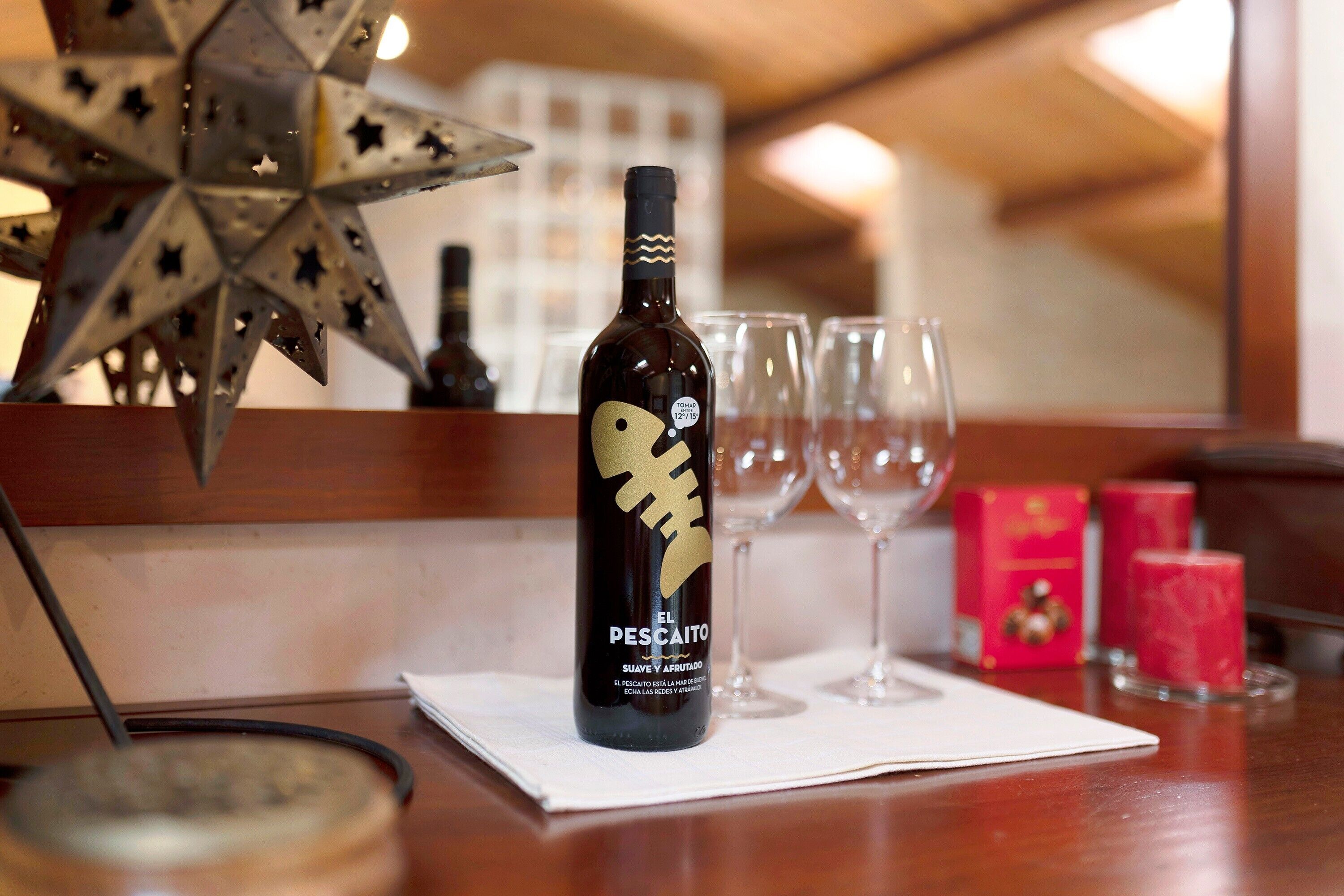 A bottle of El Pescaito wine on a table with glasses and a star decoration.