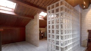 A room with a sloped ceiling, wooden beams, a glass partition with a geometric pattern, and a stone wall. - Holiday Home "Duplex India" with Wi-Fi (Tacoronte)