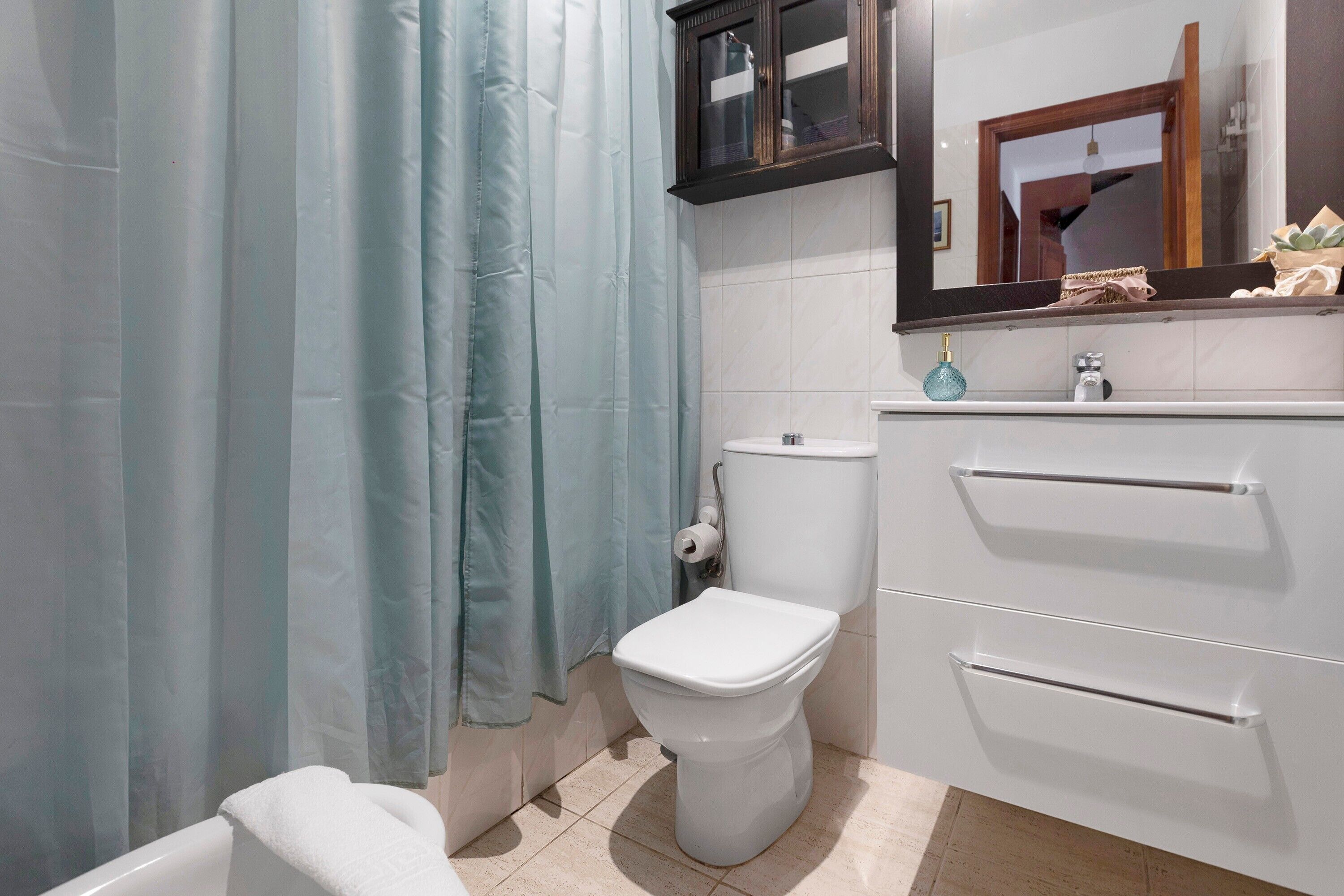 Une salle de bain équipée de toilettes, d’un lavabo, d’un miroir et d’un rideau de douche.