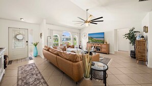Ein geräumiges Wohnzimmer mit einem braunen Sofa, einem Couchtisch und einem Deckenventilator.