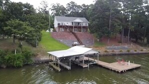 A house with a dock extending into a body of water, surrounded by trees.