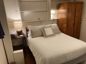 A neatly made bed with white bedding and patterned pillows, a bedside lamp, a wooden wardrobe, and a small bedside table with a tissue box. - Sunny and Spacious A-Frame nestled in the fir trees. Mountain views! (Tremont)