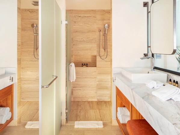 A modern bathroom with a shower, two sinks, a mirror, and a wooden floor.