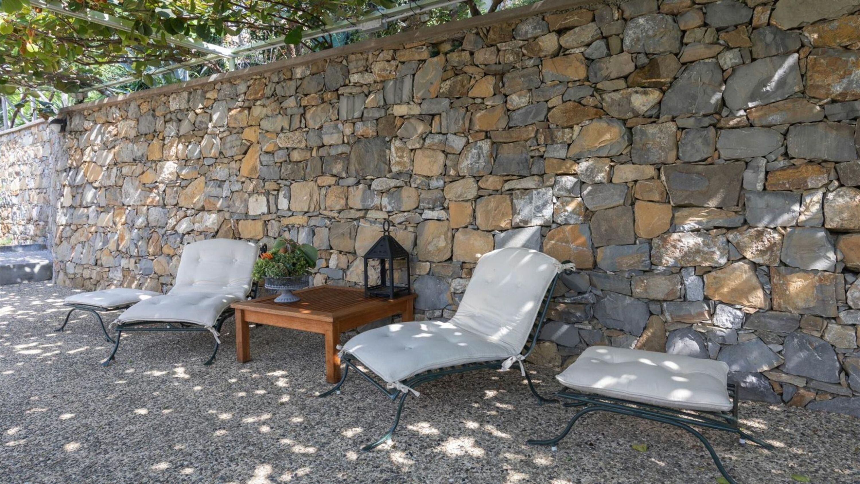 A stone wall with outdoor seating, including two chairs and a table.