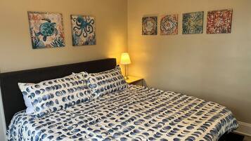 Une chambre à coucher comprenant un lit, une table de chevet et quatre œuvres d’art accrochées au mur.