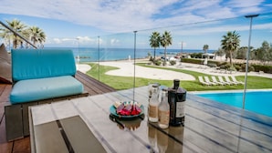 A balcony with a glass table, a blue sofa, and a view of the beach and ocean.