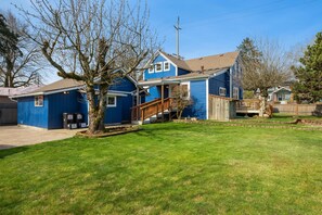 A two-story blue house with a front porch, a wooden staircase, and a well-maintained lawn.