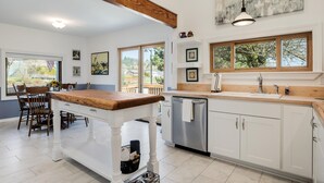 A modern kitchen with a wooden island, white cabinetry, and large windows. - The Wayside: New in the Heart of Town (Dundee)