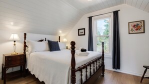 A bedroom with a wooden four-poster bed, a nightstand with a lamp, and a window with curtains. - The Wayside: New in the Heart of Town (Dundee)