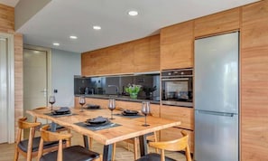 A modern kitchen with wooden cabinets, a stainless steel refrigerator, and a dining table set for four.