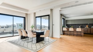 A modern apartment with a dining area, kitchen, and large windows offering city views. - Sanders Crystal 1 - Large 4-bdr Penthouse With Shared Pool (Limassol)