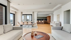 A modern living room with a sofa, a coffee table, and a dining area with chairs and a table. - Sanders Crystal 1 - Large 4-bdr Penthouse With Shared Pool (Limassol)