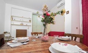 Uma mesa de jantar com pratos, copos e um vaso com flores.