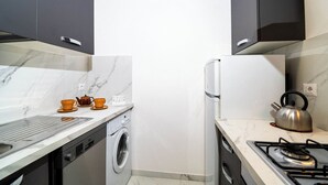 A compact kitchen with a washing machine, a gas stove, and a kettle.