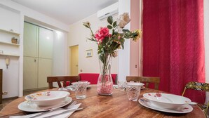 A dining table set with plates, cutlery, and a vase with flowers.