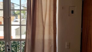 A room with a large window, a door, and a light switch on the wall.