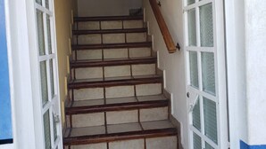 A staircase with a handrail leading to a door with glass panels.