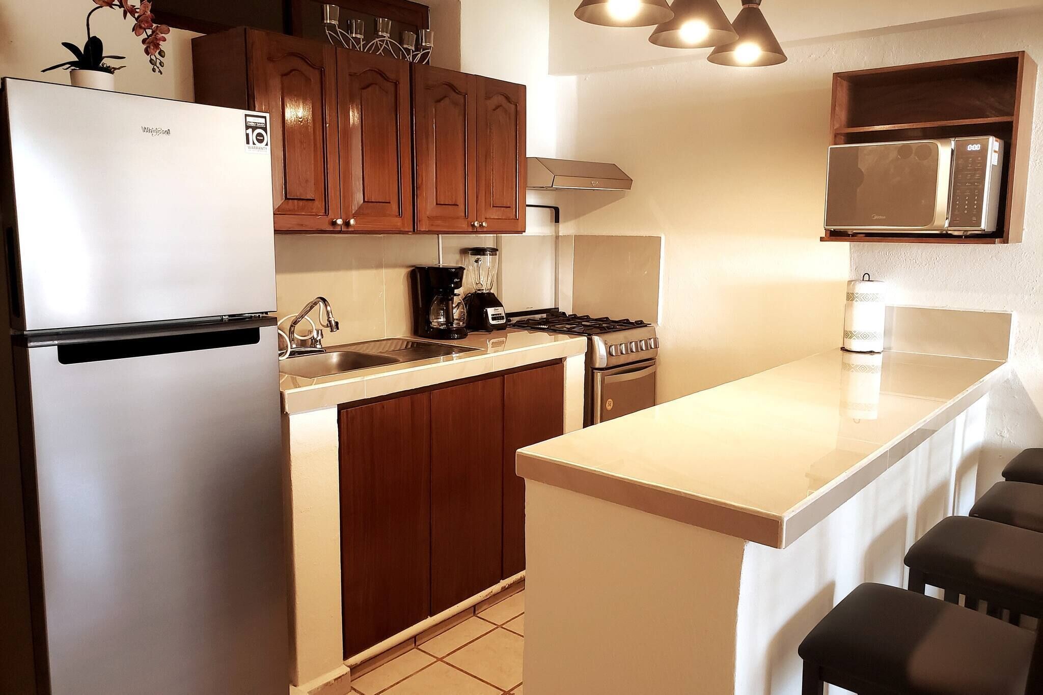 Una cocina moderna con refrigerador, estufa, microondas y cafetera.