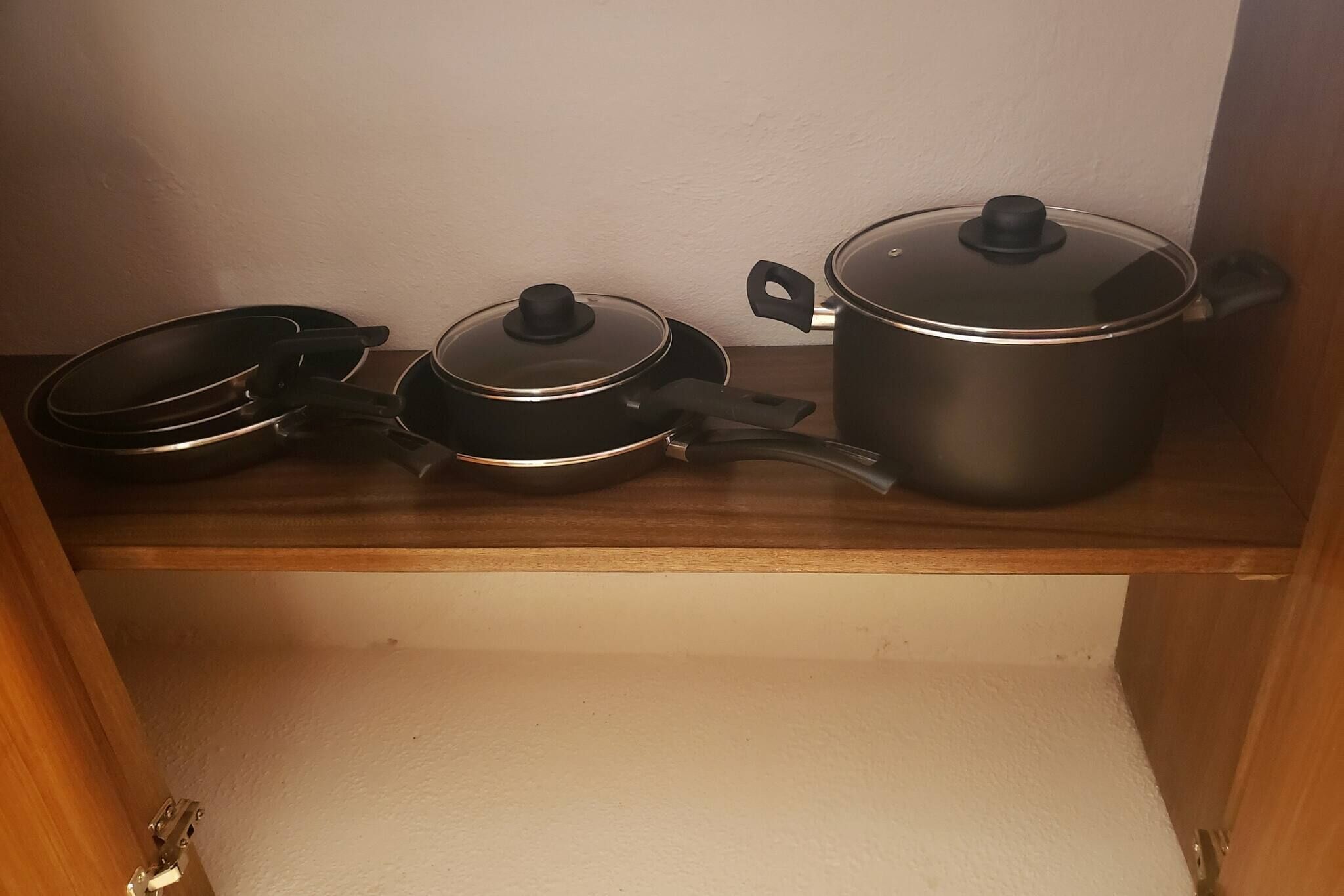 Keittiön hyllyllä on kolme kattilaa ja paistinpannua.