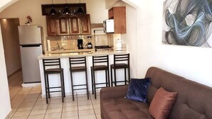 A compact kitchen with a central island, a refrigerator, and a dining area with four chairs.