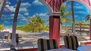 Une vue sur la plage, avec des palmiers, une plage de sable et une structure rouge dotée de sièges.